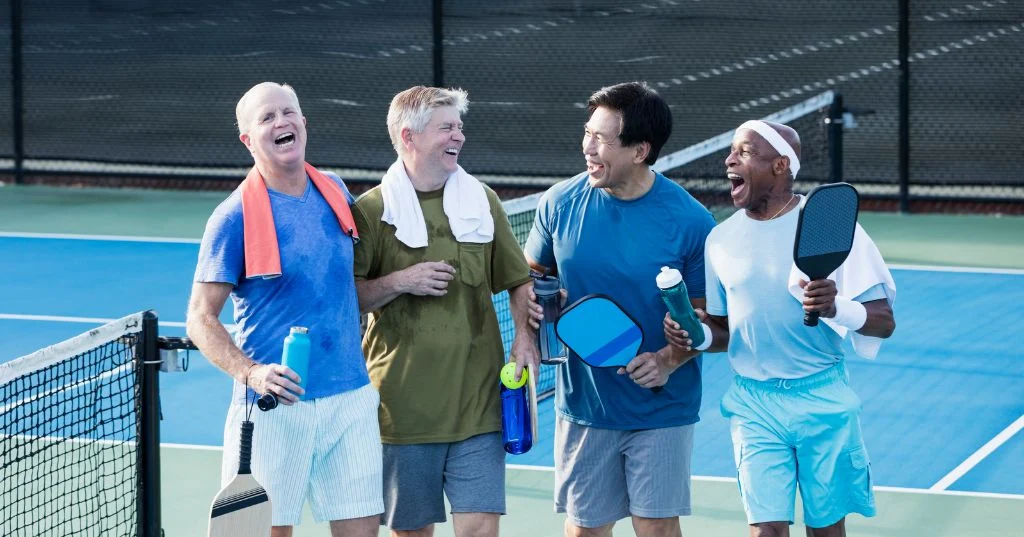Four players laughing at the net after a game